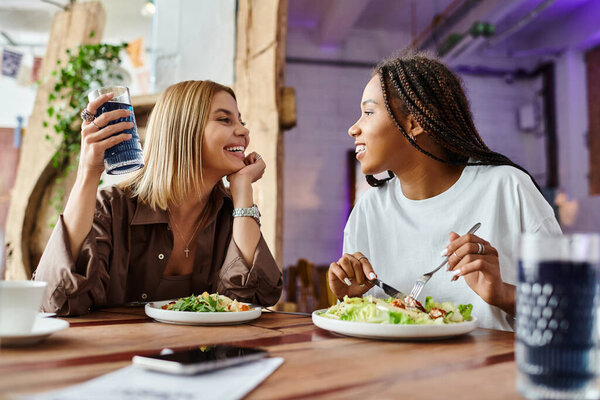 Радостный момент разворачивается, когда пара делится обедом в кафе, смеясь и наслаждаясь компанией друг друга.