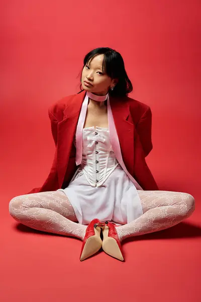 stock image An elegant Asian woman showcases a fashionable red outfit, exuding confidence and grace.