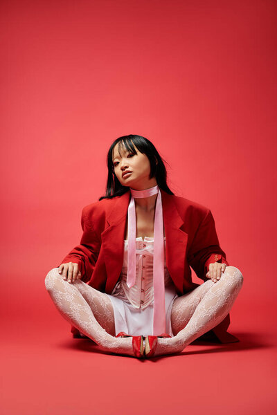 A captivating Asian woman exudes confidence wearing a striking red ensemble, seated gracefully.