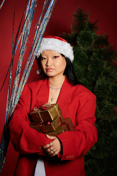 Одетая в ярко-красный пиджак, женщина радостно обнимает дух праздника, держа в руках подарки.