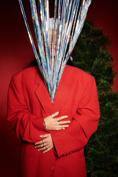 A stunning Asian woman in a vibrant red suit and eye catching decorations captures the holiday vibe.