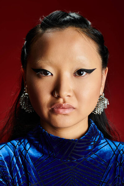 An elegant woman exudes confidence with bold eyeliner and stunning earrings in a dynamic setting.