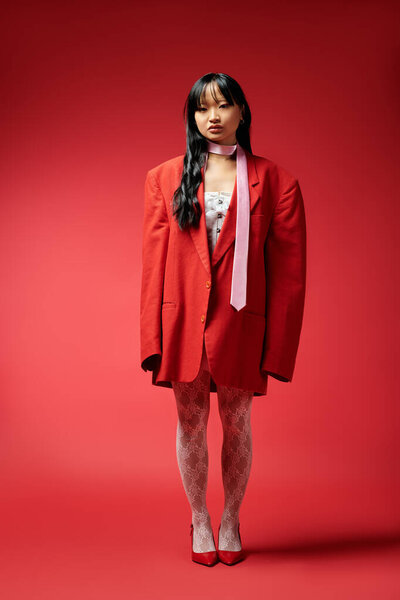 Стильная женщина демонстрирует смелую моду с огромным красным блейзером, источая уверенность и очарование.