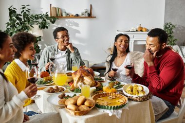 Neşeli bir grup Şükran Günü yemeğinin tadını çıkarıyor, kahkahaları, hikayeleri ve lezzetli yemekleri paylaşıyorlar..