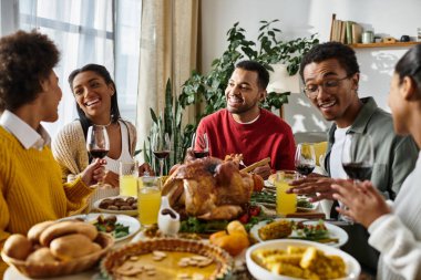 Bir grup arkadaş, kahkaha, yemek ve dostlukla dolu sıcak bir Şükran Günü toplantısının tadını çıkarıyor..
