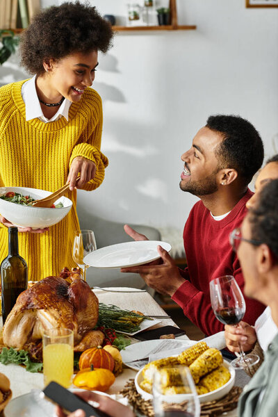 Группа друзей собирается за красиво накрытым столом, наслаждаясь Днем Благодарения вместе.
