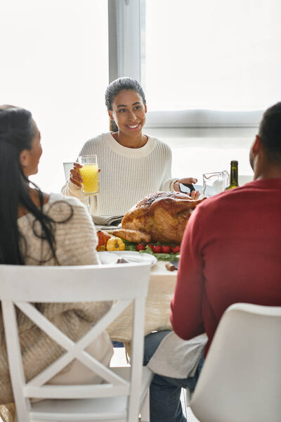 Друзья собираются за красиво накрытым столом, чтобы насладиться пиром и смехом в честь Дня благодарения..