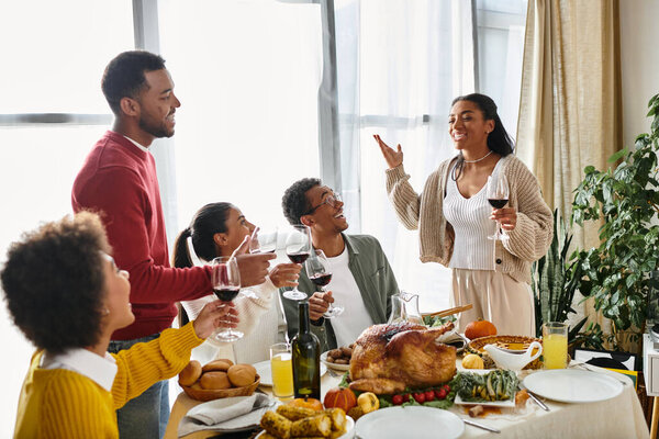 A joyful group of friends toasting with wine glasses while enjoying a festive Thanksgiving meal.