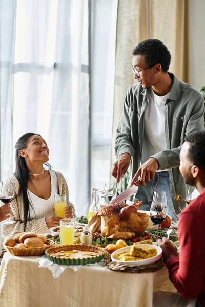 Группа друзей наслаждается Днем Благодарения вместе, делясь едой и сердечными моментами дома.