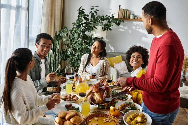 Группа друзей наслаждается ужином в честь Дня Благодарения вместе, делясь смехом и вкусными блюдами.
