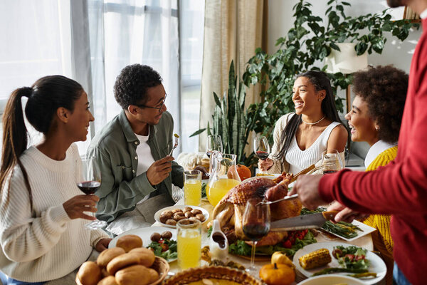 A lively group of friends shares laughter and gratitude at a festive Thanksgiving meal.