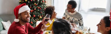Bir grup arkadaş, Noel 'i kutlarken yemek ve içeceklerin tadını çıkararak bir masanın etrafında toplanıyor..