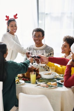 Bir grup arkadaş kutlama için bardaklarını tokuşturur, lezzetli bayram yemeklerini paylaşırlar..