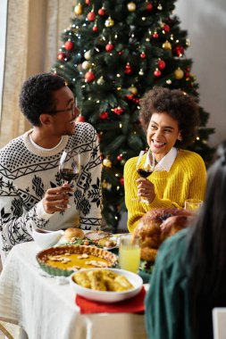 Bir grup arkadaş, kahkaha ve lezzetli yiyeceklerle dolu keyifli bir Noel toplantısının tadını çıkarıyor..