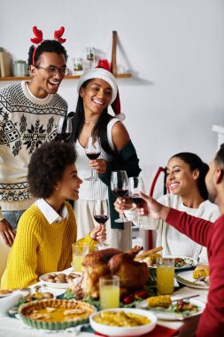 Bir grup arkadaş evde Noel ziyafeti çekerken kahkaha ve tost kadehlerini paylaşıyorlar..