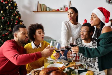 Bir grup arkadaş sıcak bir ortamda toplanıp Noel 'i kutlamak için kadehlerini kaldırıyorlar..