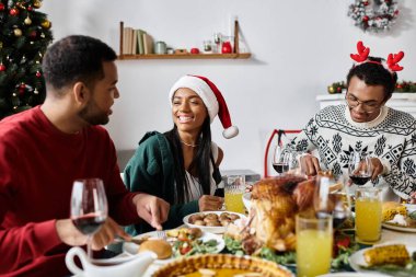 Bir grup arkadaş keyifli bir Noel yemeğinin tadını çıkarır, birlikte gülüşürler ve bayram neşesini paylaşırlar..