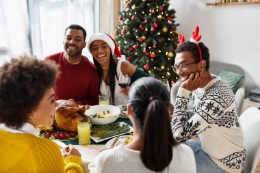 A joyful gathering of friends enjoying a festive Christmas dinner filled with laughter and love. clipart