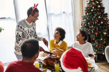 Bir grup arkadaş mutlu bir şekilde evde birlikte bir Noel yemeği yiyor, kahkahalarımızı paylaşıyorlar..