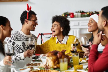 A group of friends share laughter and drinks while celebrating Christmas at home. clipart