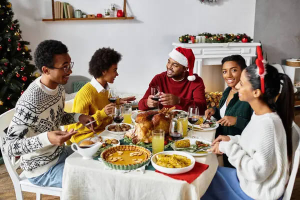 Bir grup arkadaş, kahkaha ve lezzetli yiyeceklerle dolu keyifli bir Noel yemeğinin tadını çıkarıyor..