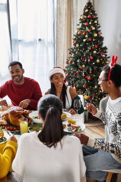 A group of friends shares a joyful Christmas dinner, surrounded by festive decorations and cheer.