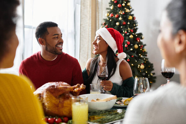 Группа друзей наслаждается праздничным рождественским ужином, смех наполняет комнату.