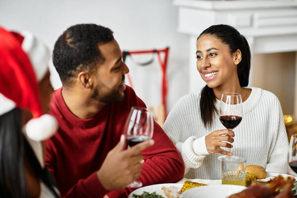 Группа друзей делится смехом и вином, наслаждаясь восхитительным рождественским праздником.