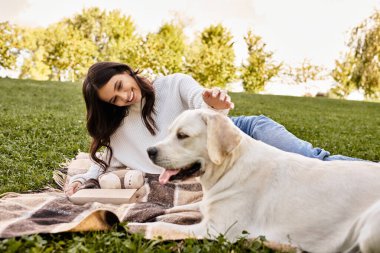 Neşeli genç bir kadın, sıcak bir sonbahar öğleden sonrasında köpeğiyle bağ kurarak dışarıda dinleniyor..