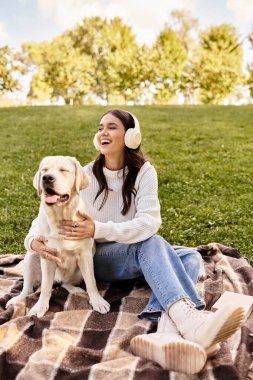 Sıcak bir sonbahar kıyafetine bürünmüş genç bir kadın köpeğiyle güneşli bir günün tadını çıkarıyor..