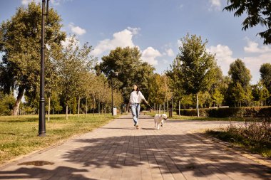 Genç bir kadın, güzel bir sonbahar günü için sıcak tutacak şekilde parkta rahatça yürümekten zevk alıyor..