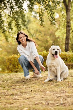 Samimi giyinmiş genç bir kadın köpeğiyle huzurlu bir anın tadını çıkarırken sıcacık gülümsüyor..