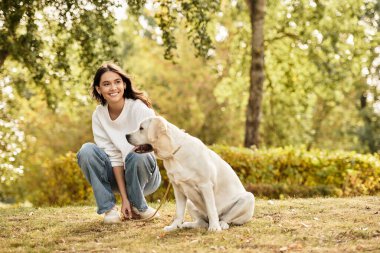 Sıcak sonbahar giysileri içindeki kadın dışarıda köpeğiyle neşeli anlar geçirirken gülümsüyor..
