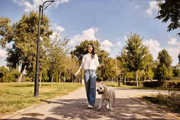 Samimi sonbahar kıyafetleri giymiş güzel bir kadın köpeğiyle parkta geziniyor..