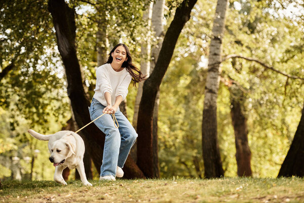 A joyful young woman in cozy autumn attire plays with her dog amidst fall colors.