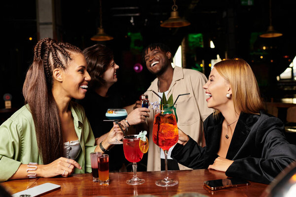 Молодые профессионалы празднуют вместе с коктейлями и улыбаются на оживленном корпоративном собрании.