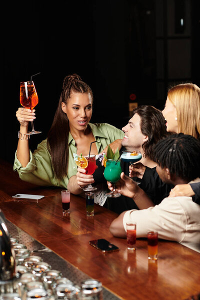Молодые профессионалы тост с красочными напитками на оживленном корпоративном собрании.