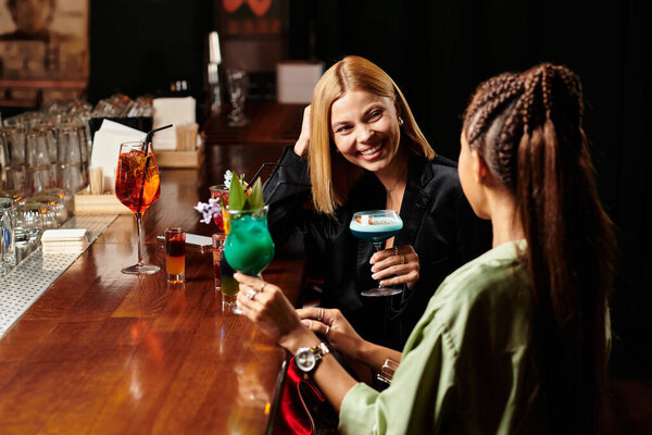 Два молодых профессионала ведут оживленную беседу, наслаждаясь красочными коктейлями.