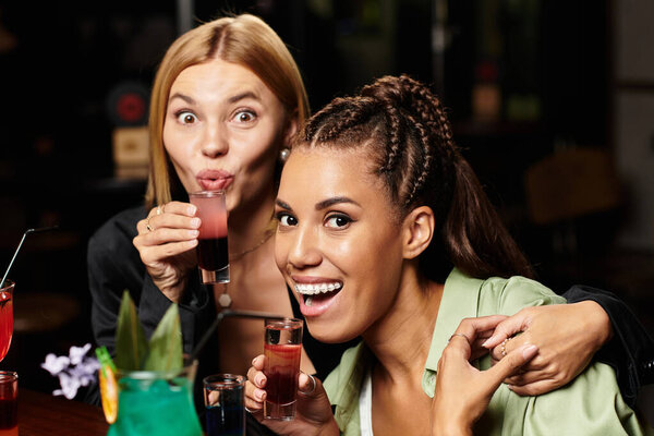 Два веселых коллеги кудахтают вместе, наслаждаясь веселым моментом на вечеринке.