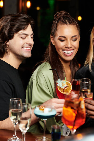 Коллеги празднуют вместе с коктейлями, делятся улыбками и смехом на оживленном мероприятии.