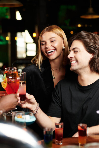 Молодые профессионалы смеются и тосты на корпоративной вечеринке, делясь памятными моментами.