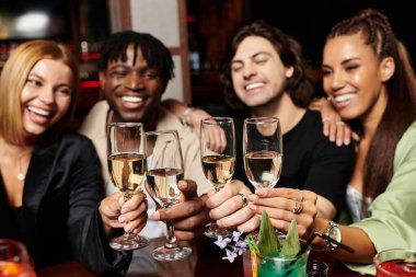 Young colleagues joyfully raise their glasses in celebration at a lively corporate event. clipart