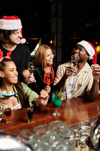 Группа молодых профессионалов смеется и тосты с напитками во время праздничного корпоративного собрания.