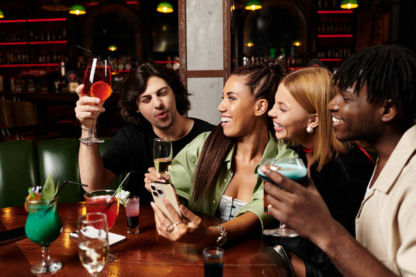 Коллеги наслаждаются веселым вечером вместе, делясь напитками и смехом на корпоративном собрании.