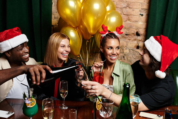 Коллеги собираются веселыми, наслаждаясь праздничными напитками и делясь смехом на радостном празднике.