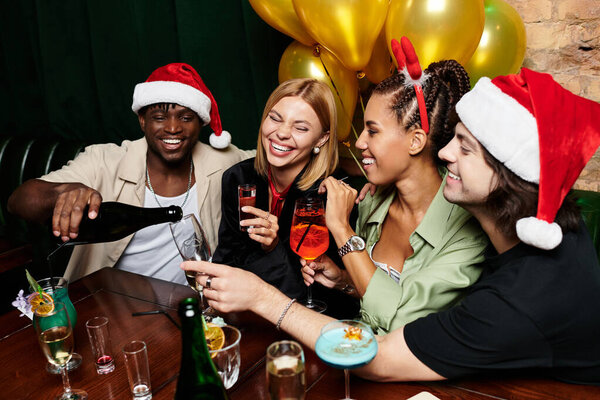 A group of young colleagues enjoy a festive celebration, sharing laughter and drinks together.