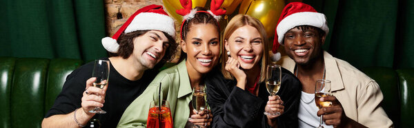 Young professionals enjoy festive drinks and laughter during a corporate holiday celebration.