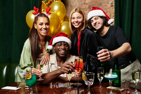 A group of young diverse colleagues toasts with colorful drinks during a festive celebration.