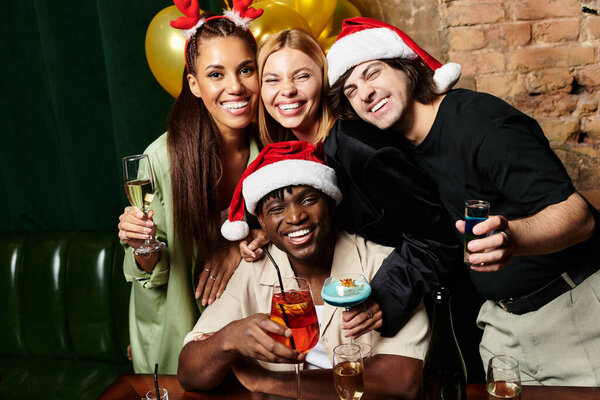 Young colleagues celebrate the season with drinks and laughter at a festive corporate gathering.