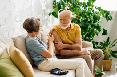 A senior couple shares a tender moment as the wife helps her husband manage his diabetes. clipart